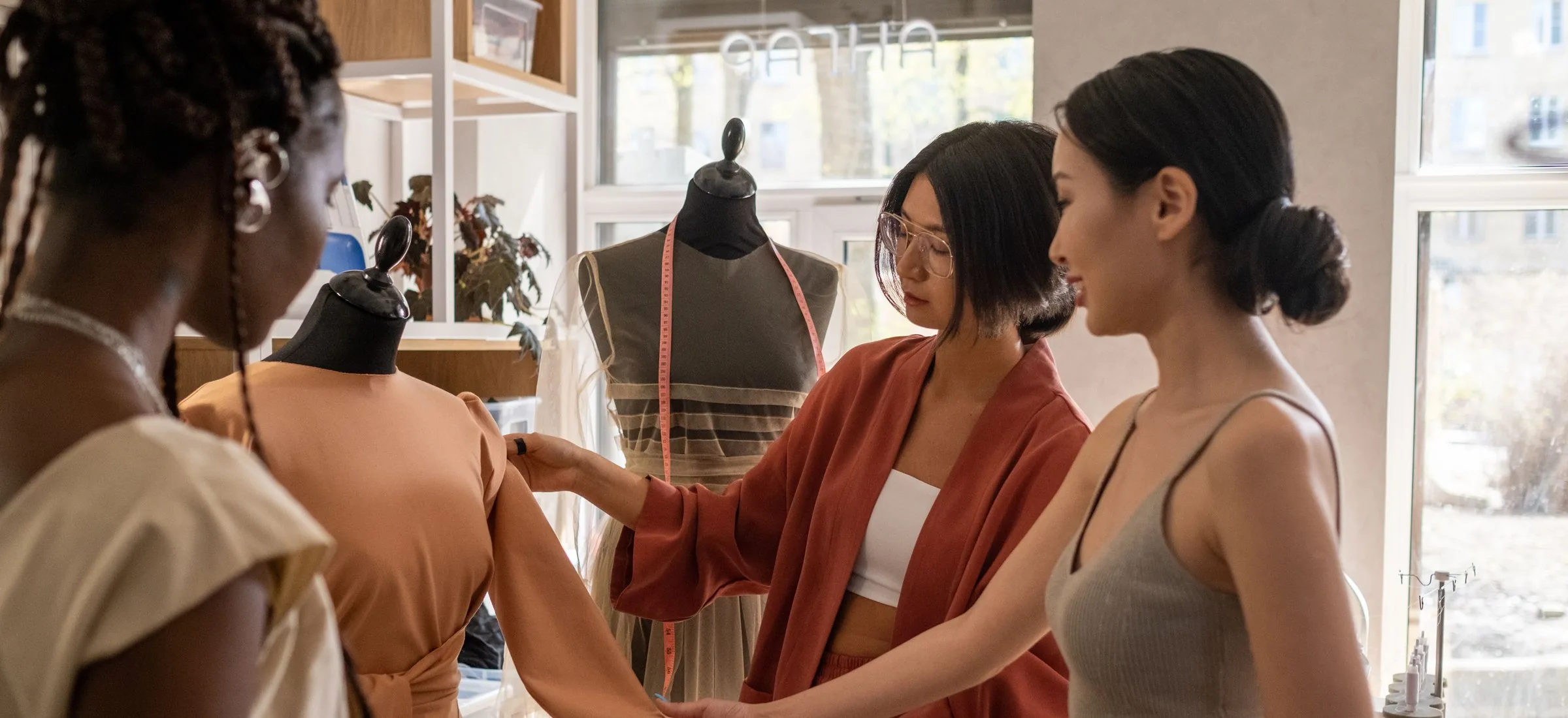 Designers fitting a dress on a mannequin in a bright clothing studio